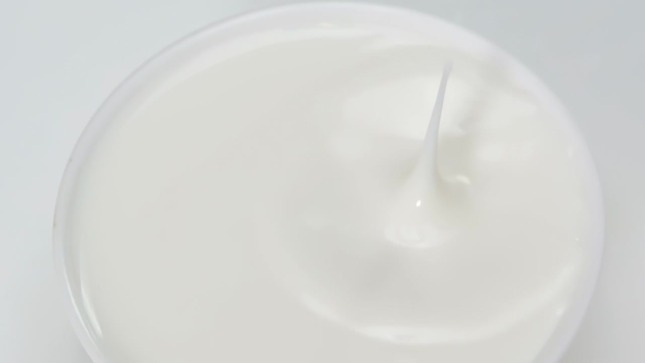 Gocce fresche di latte che cadono e si spruzzano su una superficie serena dall'alto, oppure primo piano di gocce di liquido bianco che impattano su pozze bianche.