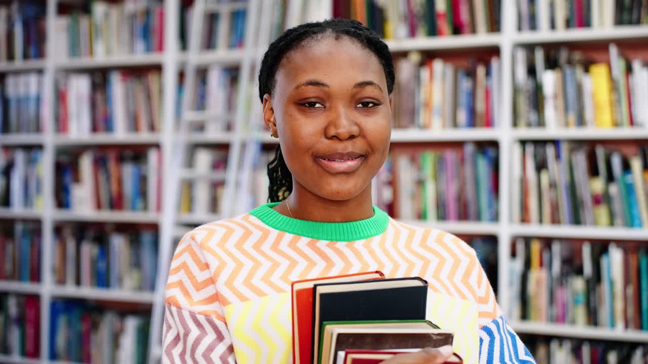 Smiling Young African American Woman Holding Books in a Library