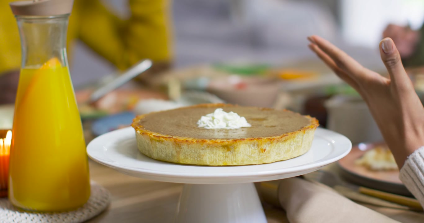 Afro-Amerikan çift evde konuşuyor, yemek sırasında eller tabaklara uzanıyor, ayaklı tabakta tart.