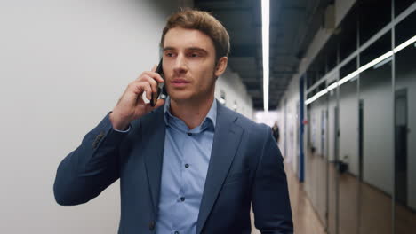 smiling manager speaking phone walking business center hallway alone portrait.