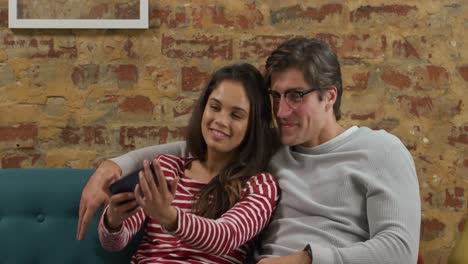 pareja caucásica tomando una selfie en un sofá
