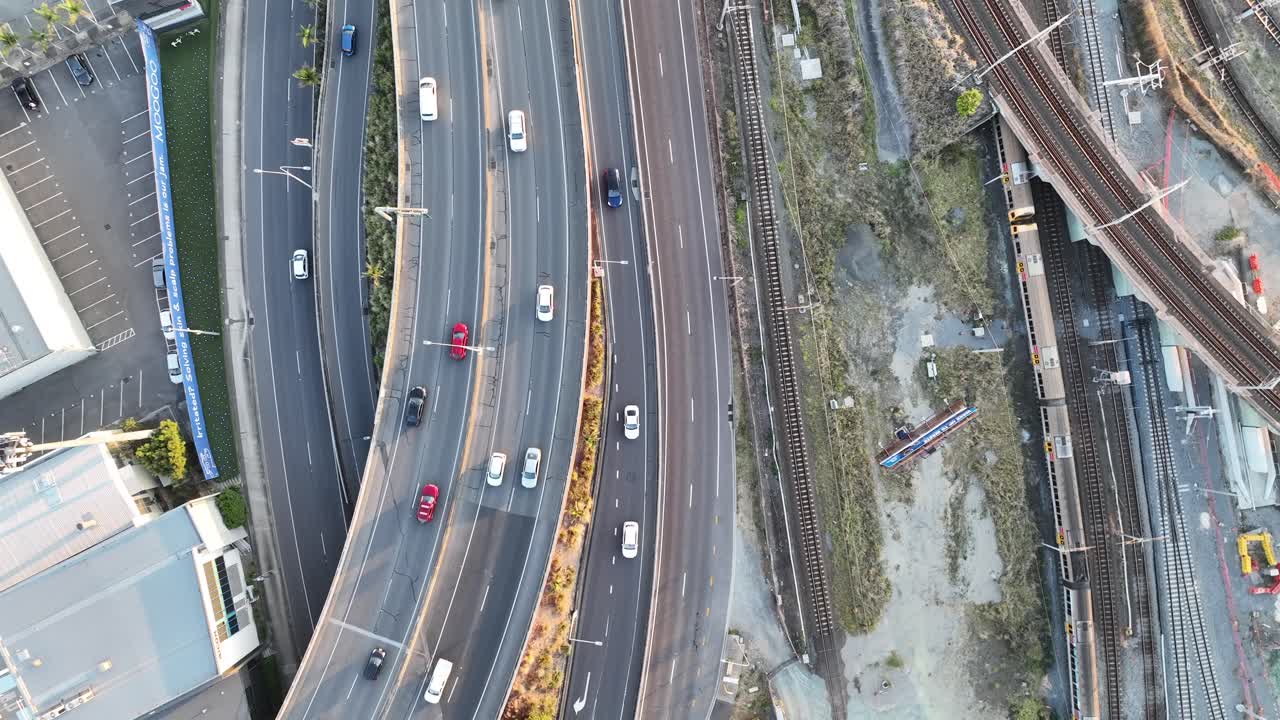 Top down shot from above Brisbane City's Mayne Railway Yard, as a train passes through the shot, Busy car traffic on road leading to ICB inner city bypass