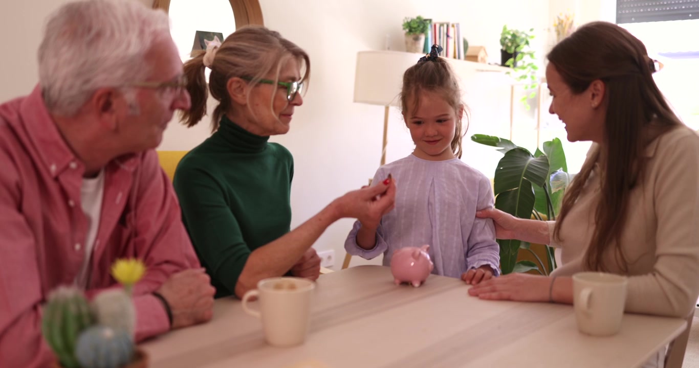 Family Teaching Young Girl to Save Money in Piggy Bank