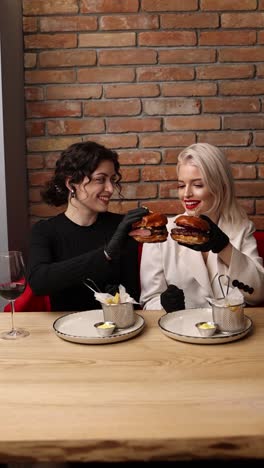 dos mujeres disfrutando de hamburguesas en un restaurante