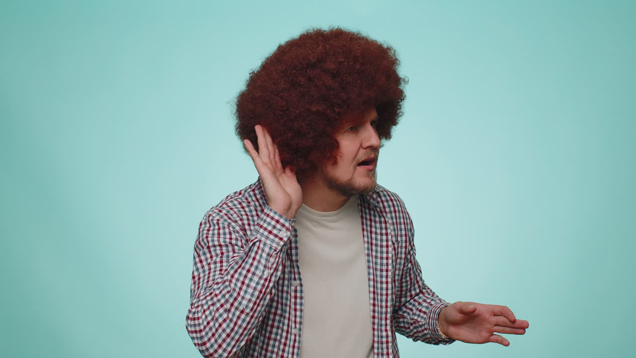 hombre tratando de oírte, mirando confundido y fruncido el ceño, manteniendo el brazo cerca de la oreja para una voz más alta, repetir