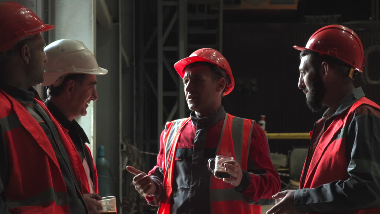 Industrial Workers in Hard Hats and Safety Vests Talking During Break