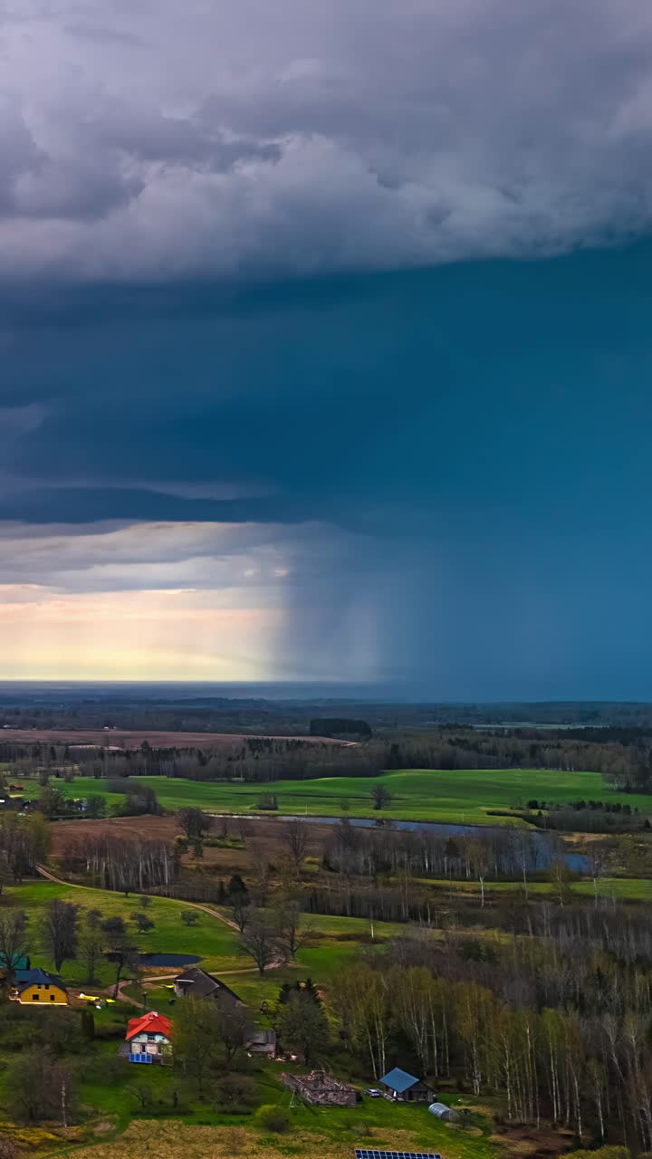 Storm clouds roll in during vertical timelapse above farmland and distant countryside hill