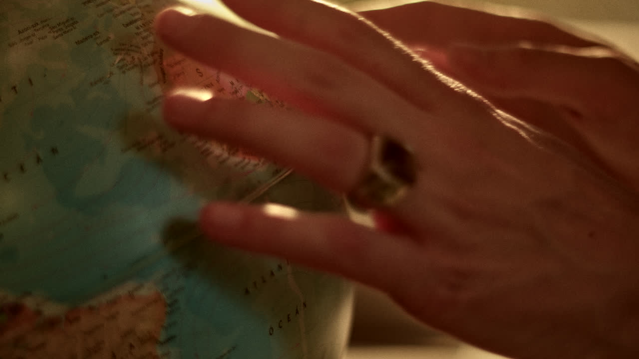 A person's hand interacting with a vintage globe under warm lighting