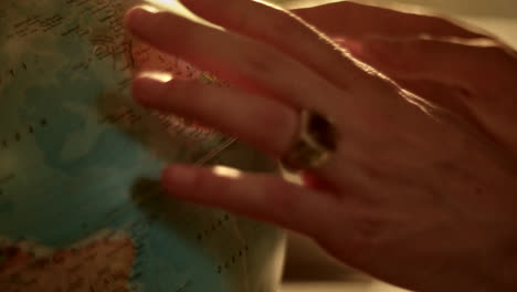 a person's hand interacting with a vintage globe under warm lighting