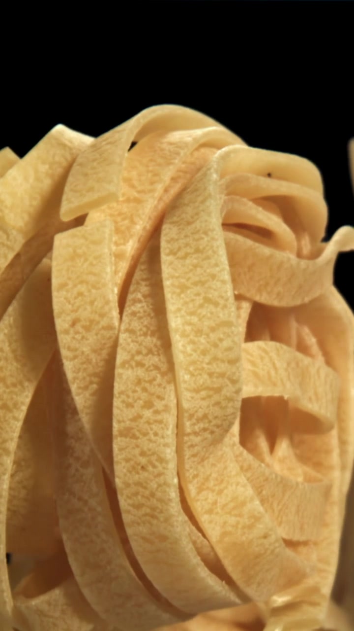 Tagliatelle secche che si sollevano su sfondo nero