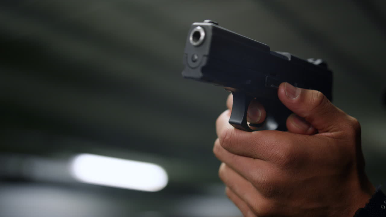 경찰의 손은 총을 겨냥하고 있다. 남성 경찰은 총의 방아 ⁇ 에 손가락을  ⁇ 고 있다.