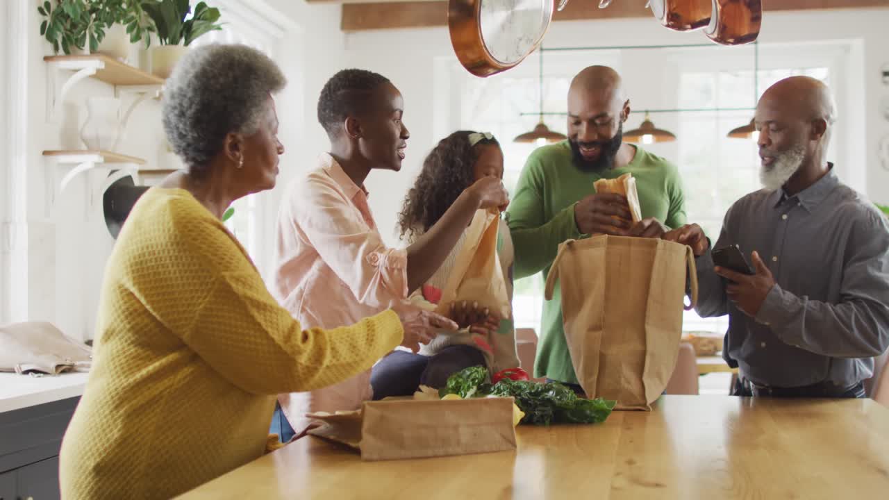 Video of happy african american parents with daughter and grandparents, arriving home with shopping