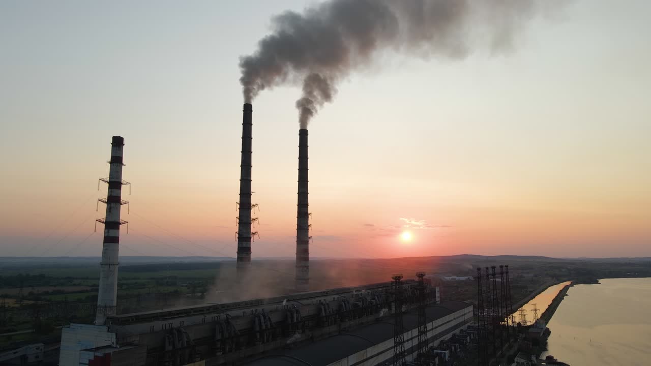 Vista aerea dei tubi alti della centrale elettrica a carbone con fumo nero che si muove verso l'alto atmosfera inquinante al tramonto. Produzione di energia elettrica con il concetto di combustibili fossili