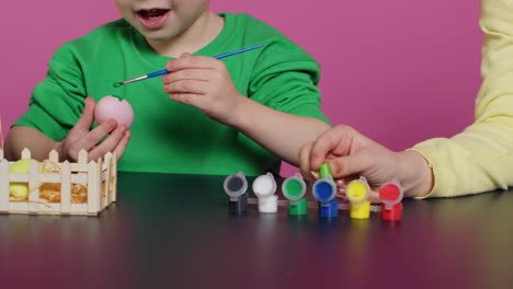 niños adorables coloreando huevos de pascua con pintura acuarela