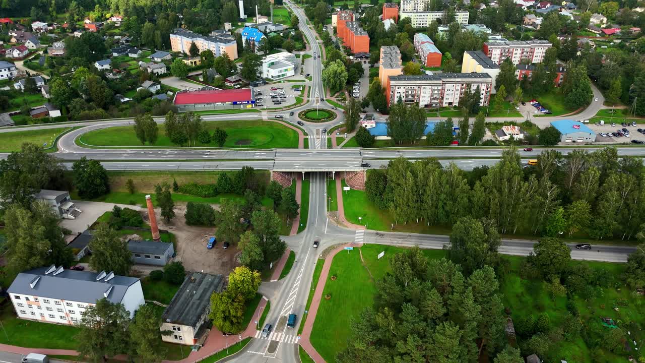 Drone pullback across highway and Ikskile roundabout and green surroundings with clear summer skies