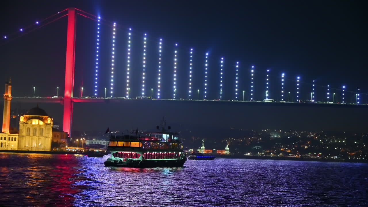İstanbul, Türkiye’de gece Boğaz manzarası. Yüzen gemi, arabaların olduğu ışıklandırılmış köprü, arka planda binalar.