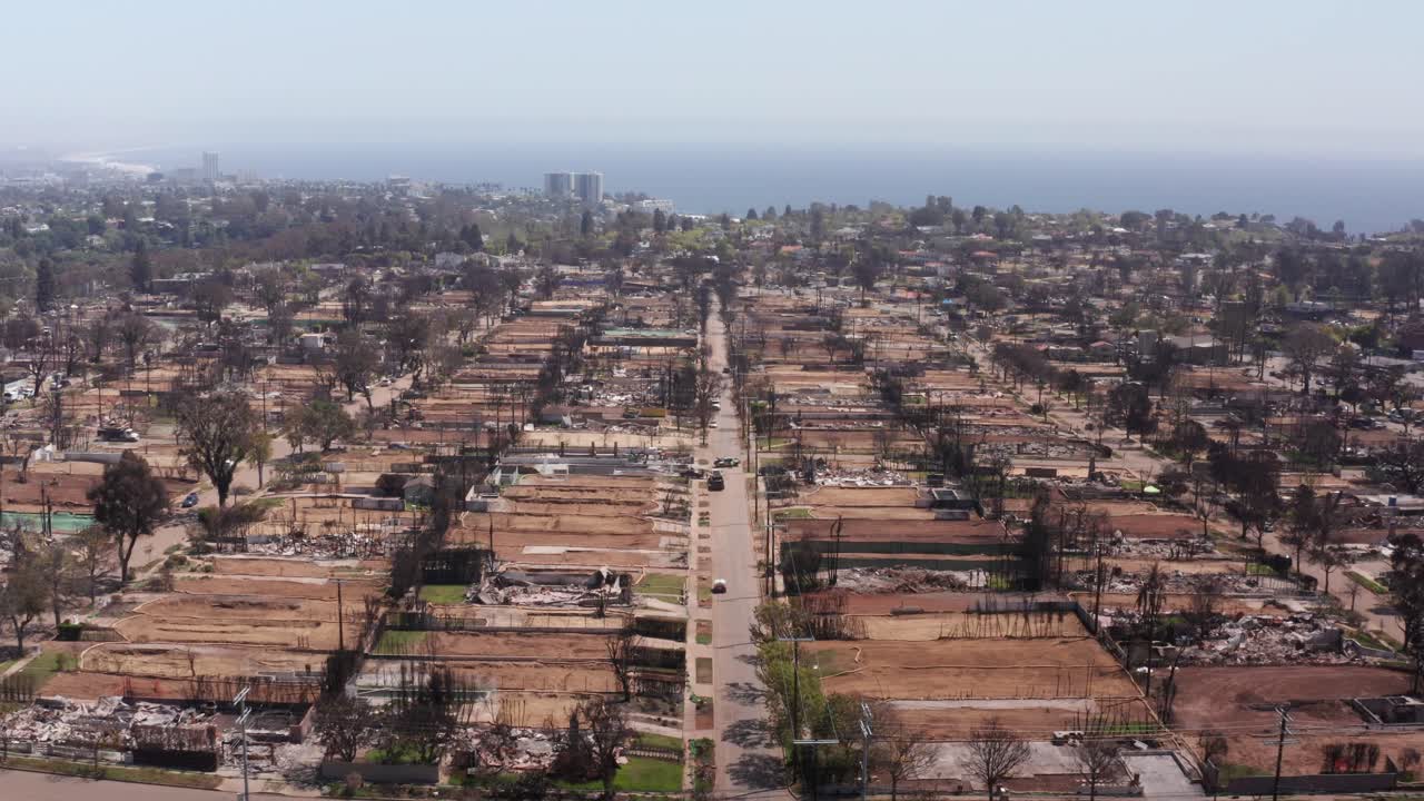 Aerial descending shot flying over scorched residential lots in Pacific Palisades after the Palisades Fire in Los Angeles, California. 4K