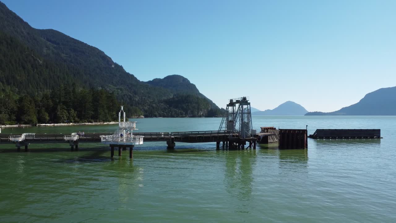 A tranquil scene of Britannia' s Porteau Cove aerial view from a drone reveals the beauty of nature with its blue ocean water, towering mountain range and lush forest