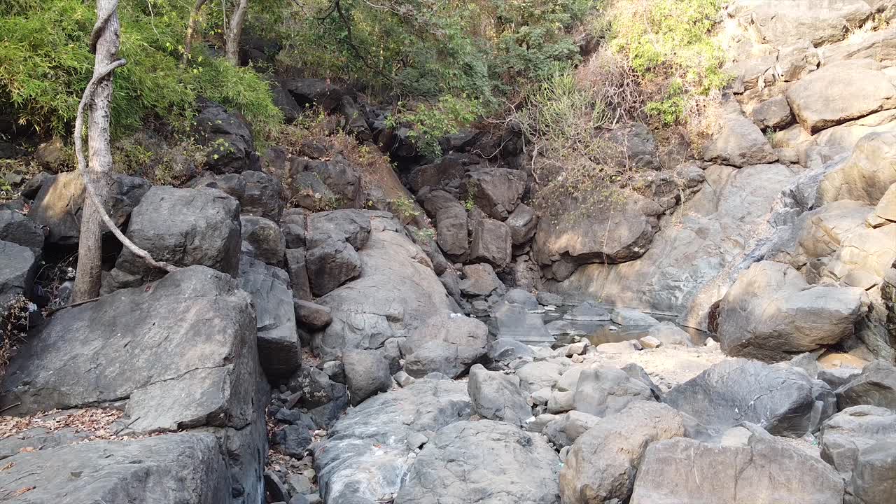 una cascada seca y un pequeño estanque de agua en el fondo del video de un dron del bosque