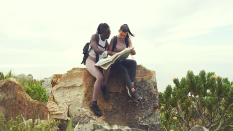 Two-women-hiking-looking-at-map-sitting-on-a-rock