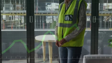 green graph forming and arrows going down against female architect zipping up her hi-vis vest