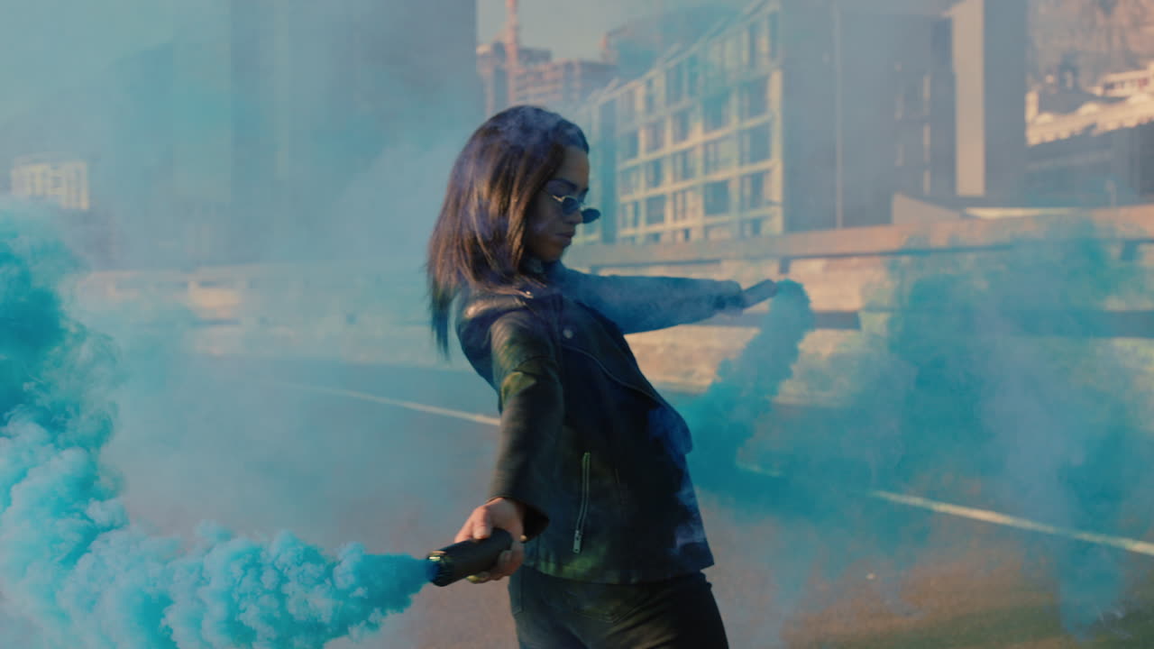 девочка танцует с голубой дымовой гранатой в городе молодая мятежная женщина празднует творческое выражение танцем на улице в замедленном движении