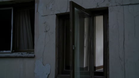 abandoned apartment building with cracked paint and open windows