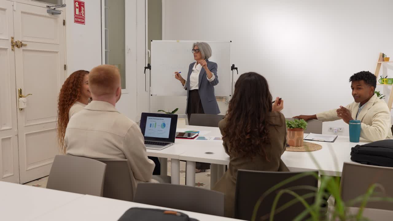 Team aziendale eterogeneo che assiste a una presentazione in un ufficio moderno