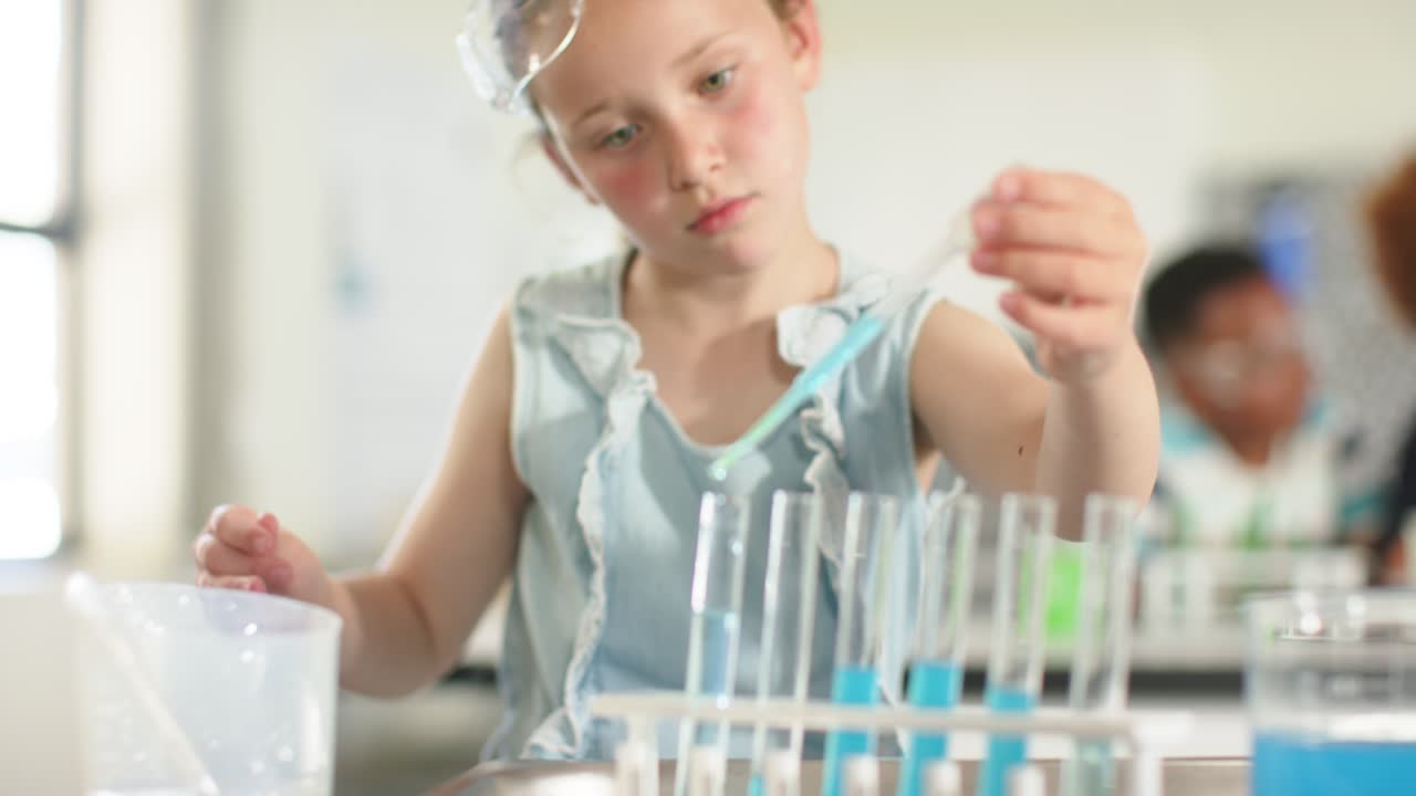 Ragazza in età scolare con occhialini che ispeziona provette, prelevando liquido blu con una pipetta in laboratorio per un esperimento scientifico.
