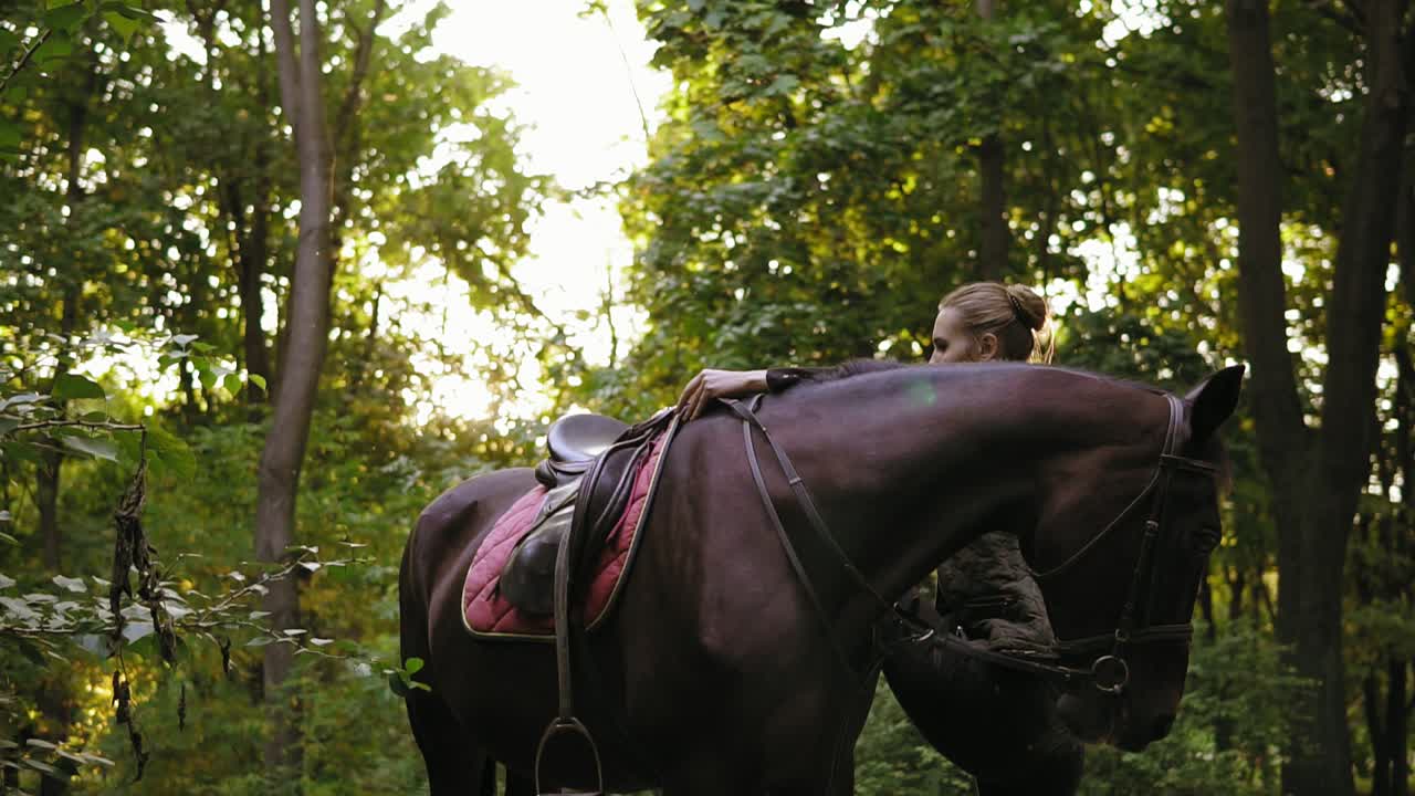 mujeres ecuestres suben a caballo con la ayuda de un estribo durante un día soleado en el bosque