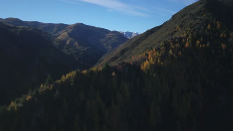 Drone-panning-shot-of-Autumn-colored-trees-on-the-mountains-where-sunlight-falling-over