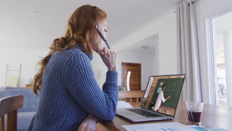 caucasian female student using laptop and phone headset on video call with male teacher