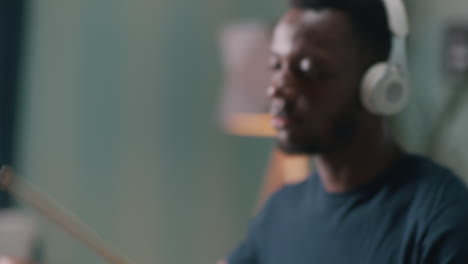 focused black male musician playing drums rack focus of concentrated african american man in wireless headphones playing rhythmic song on drums in light home studio