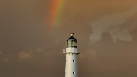 cape egmont lighthouse with moody cloud background and rainbow