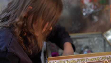 close up of surprised and excited young girl opening box with presents in front of christmas decoration with gifts and packages on santa sledge