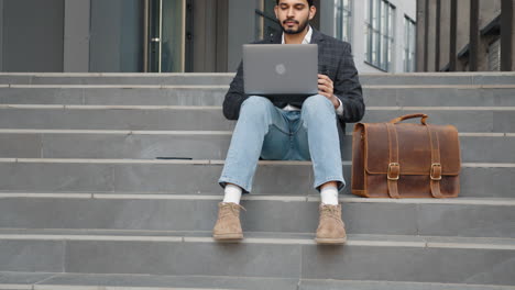 hombre de negocios trabajando en una computadora portátil al aire libre en las escaleras