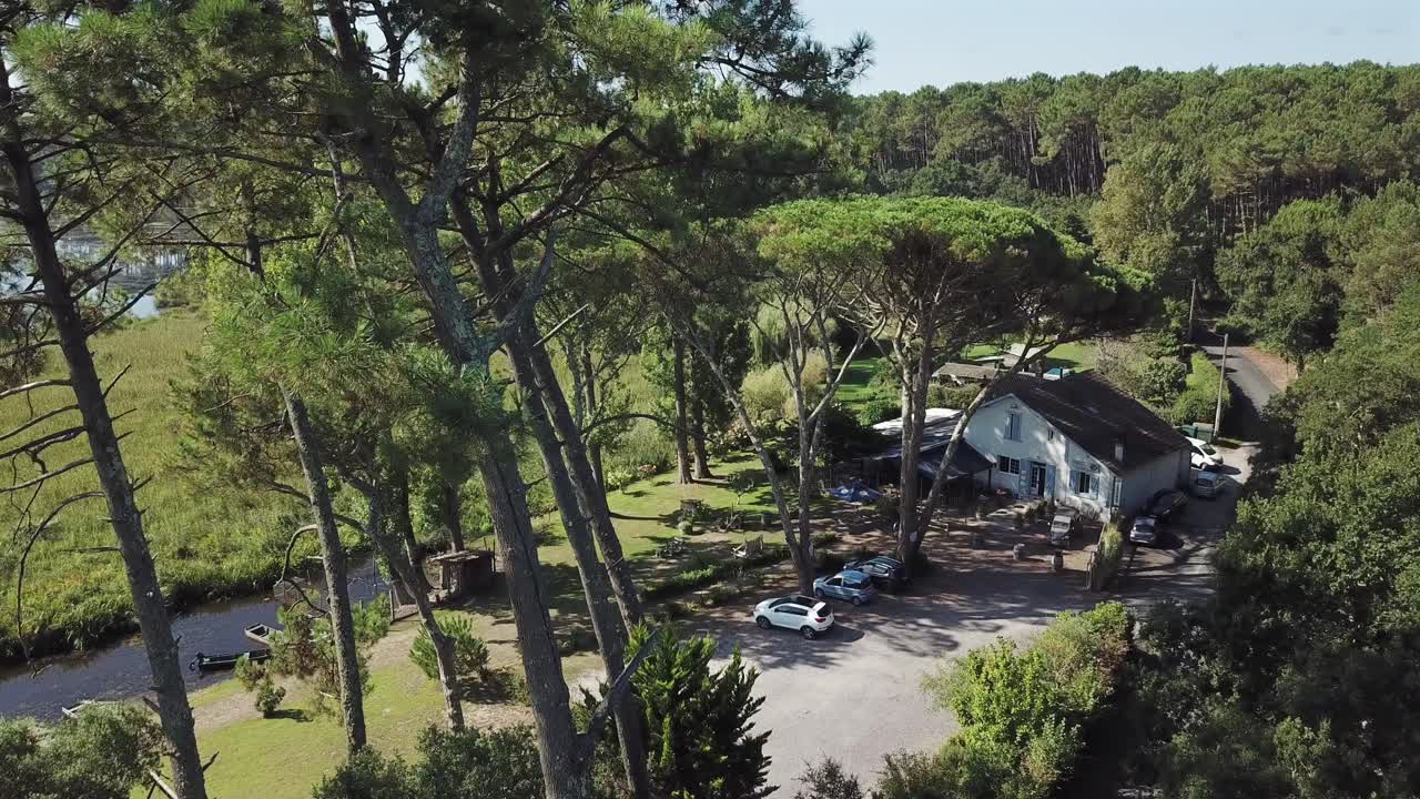 Lakeside, house surrounded by pines, Landes, France. Aerial forward