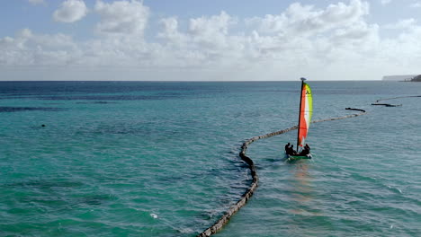 Family-sailing-on-small-catamaran-on-tropical-beach,-idyllic-seascape-in-Caribbean-sea,-aerial-view