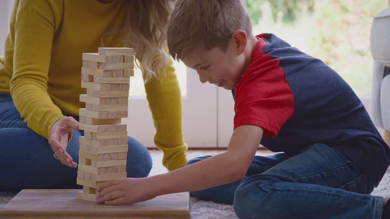 Mother And Son At Home Playing Game Stacking And Balancing Wooden Blocks Together