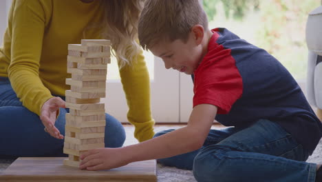 mother and son at home playing game stacking and balancing wooden blocks together