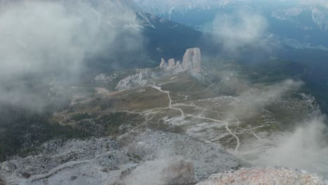 ascending backwards flight over summit of averau peak with clouds, cinque torri towers, dolomites