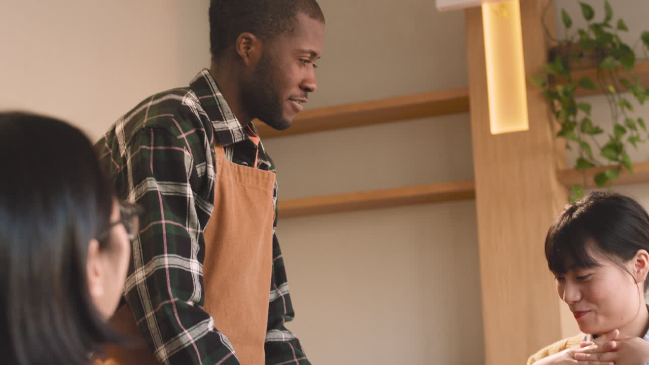 Woman Talking With Her Male Friend Sitting In A Coffee Shop While Waiter Serving Her Food