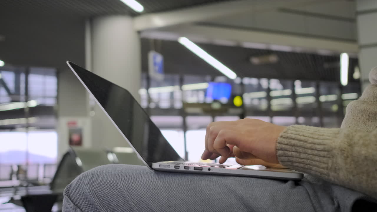 persona que trabaja en una computadora portátil en el aeropuerto
