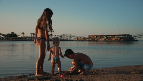 Happy-teenagers-having-fun-with-cute-baby-boy-on-sand-beach-at-sea-resort.