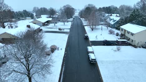 A-snowy-residential-street-with-duplex-homes-and-bare-trees