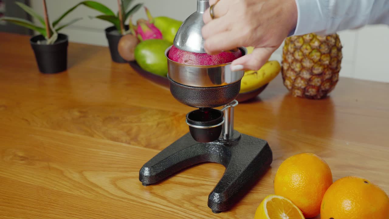 Caucasian woman using hand press fruit juicer making fresh apple juice, close up