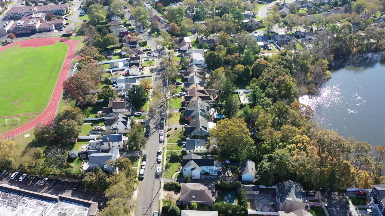 그랜트 연못의 공중 드론 보기, 긴 섬, 뉴욕 교외의 카메라 트럭 오른쪽, 태양이 수면에 비치는 동안 연못 위로 기울어져 밝게 반짝임