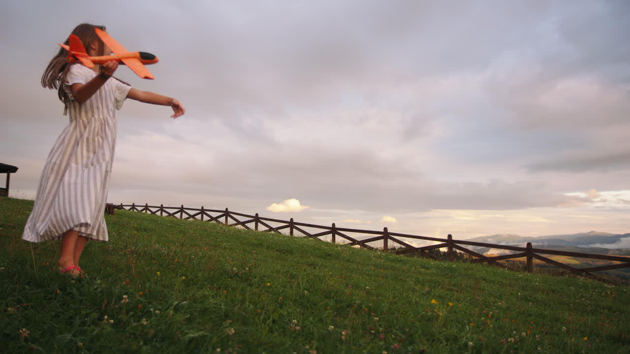 Girl playing with toy airplane in a mountain meadow