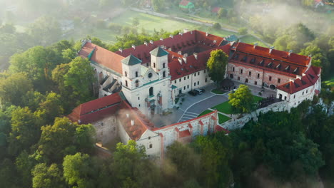 Aerial-drone-view-of-Benedictine-Abbey-over-Vistula-river-in-Tyniec-in-the-morning-fog,-Krakow,-Poland