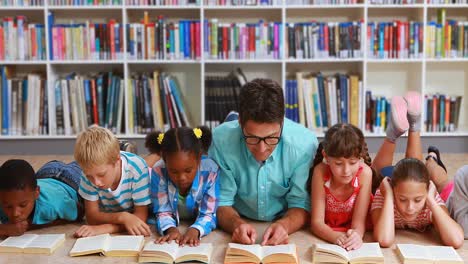 teacher and kids lying on floor reading book in library